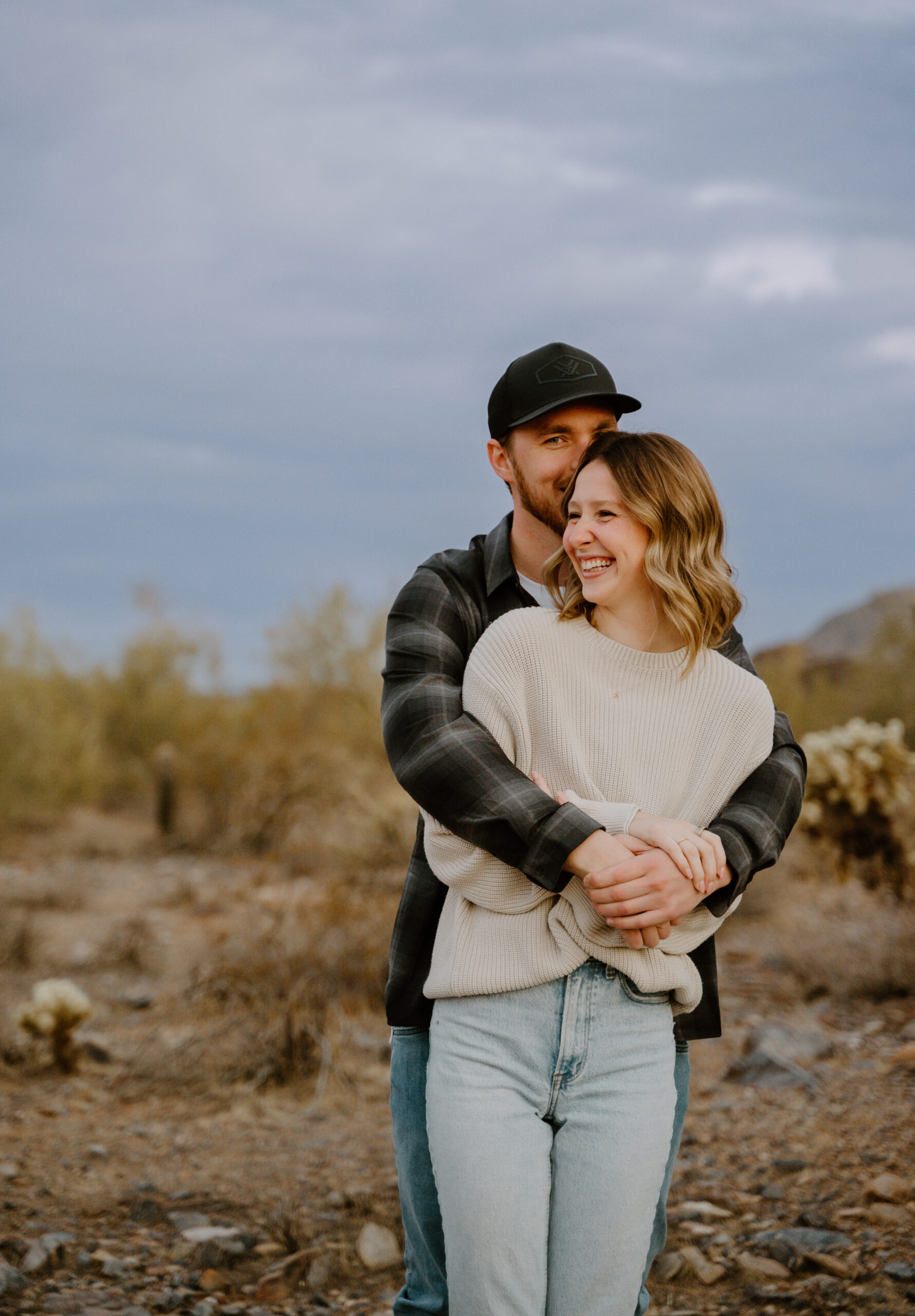 A close-up of a couple smiling and embracing in the Arizona desert, showcasing the intimacy and warmth of engagement sessions in stunning desert locations.