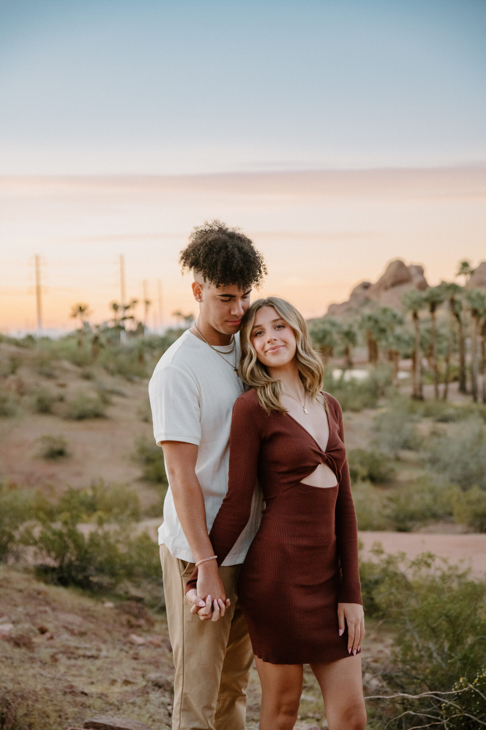 A stylish couple poses in front of Papago Park's red rock formations and palm trees, showcasing one of the most diverse and scenic Arizona engagement session locations.