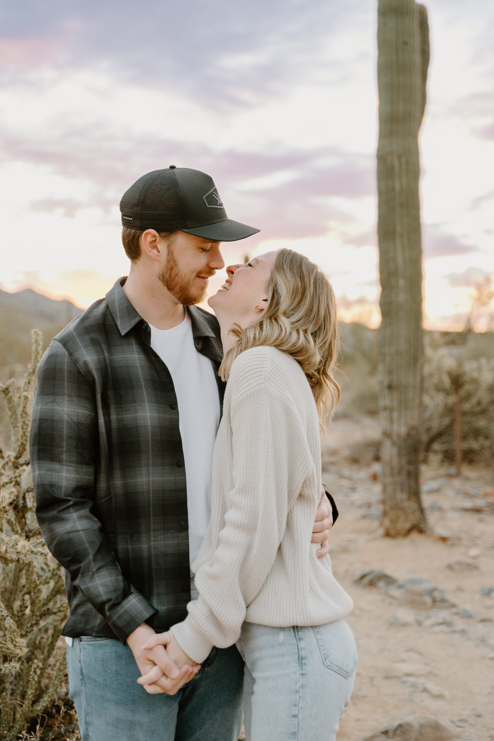 An intimate sunset moment as a couple embraces with the Arizona sky glowing in the background, showing why engagement sessions in Arizona offer some of the most breathtaking landscapes.