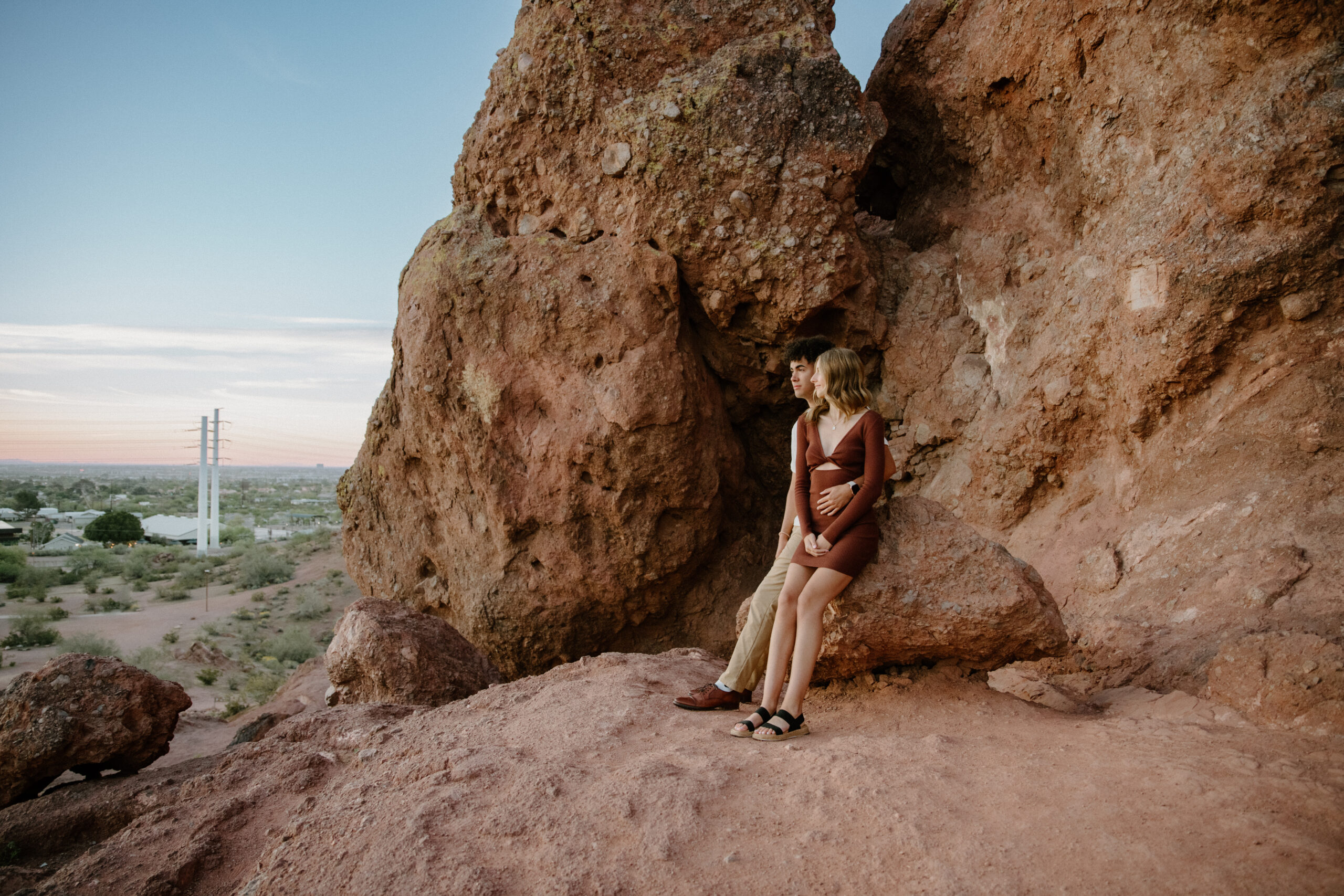 A stylish couple poses in front of Papago Park's red rock formations