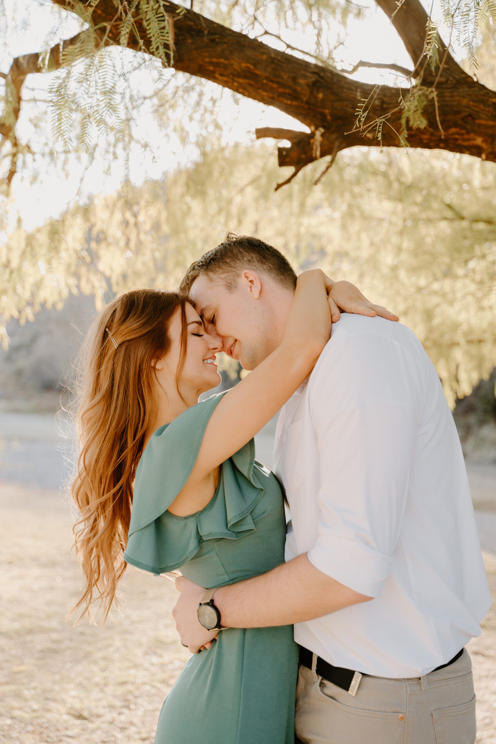 Couple embraces at Saguaro Lake sunset smiling at one another