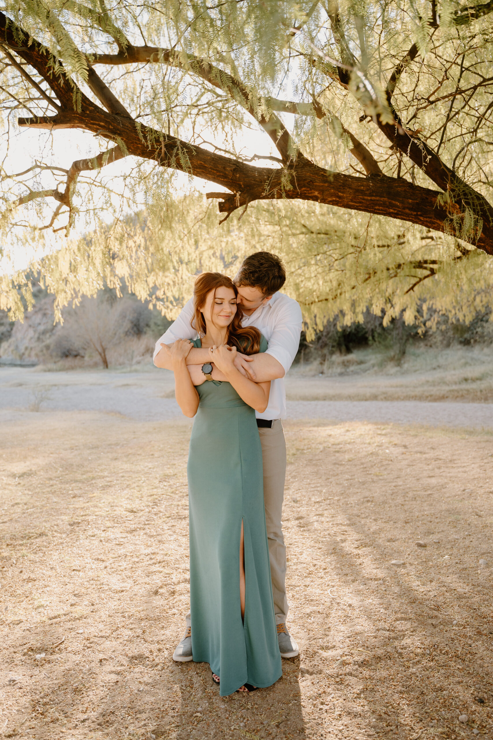 Couple embraces at Saguaro Lake during sunset smiling at one another