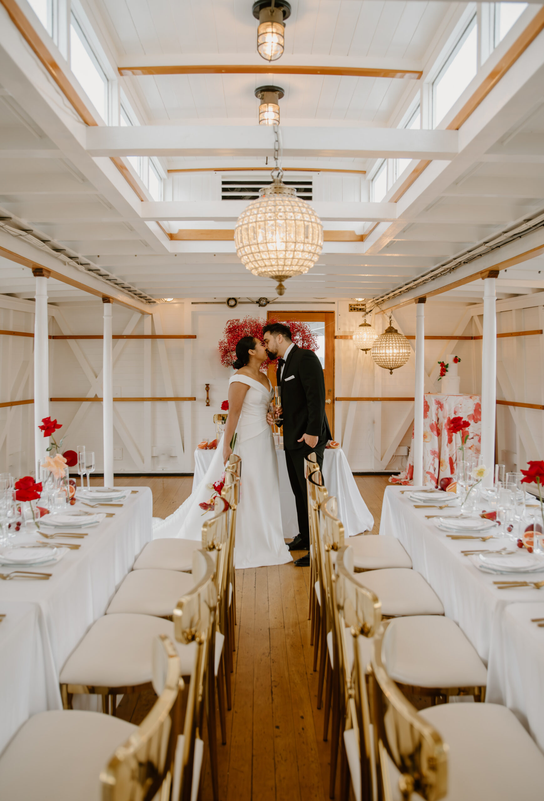 Wide view of the lower deck set for a boat wedding reception with chandeliers and modern floral decor.