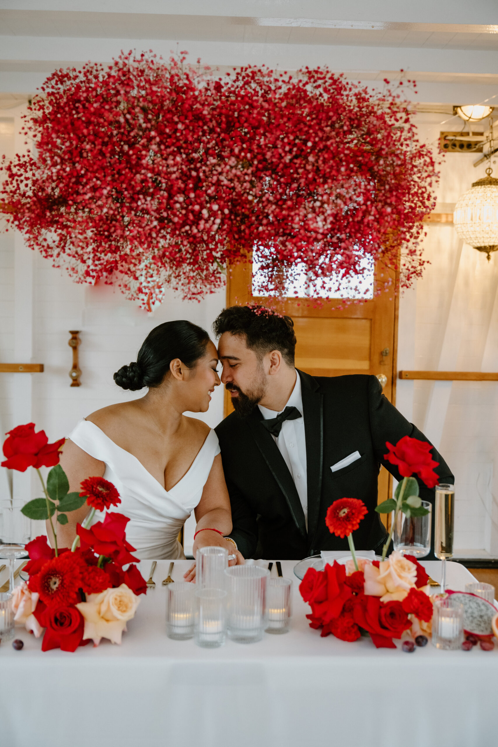 Bride and groom touching foreheads while sitting at their sweetheart table during their boat wedding reception.