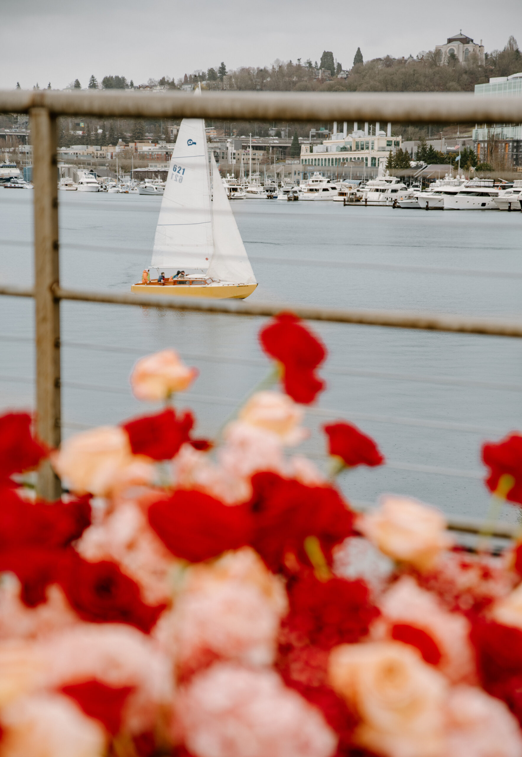 Sailboat floating in the harbor beyond vibrant wedding florals during a Virginia boat wedding celebration.