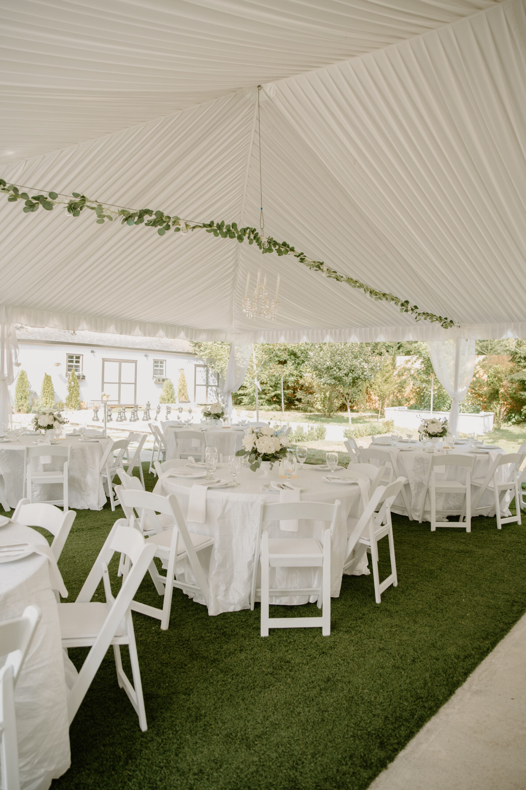 Wide view of elegant reception tent with chandeliers and white table settings at Jackson Manor Events.