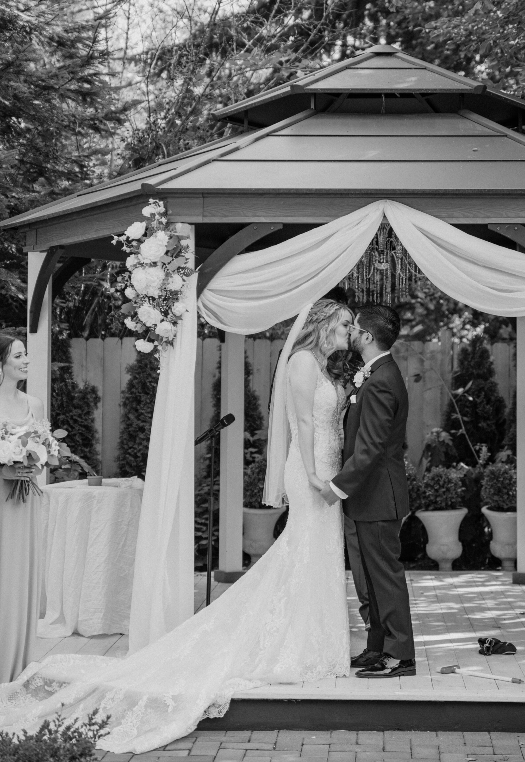 The bride and groom share their first kiss under the elegant draped gazebo during their Jackson Manor Events wedding ceremony.