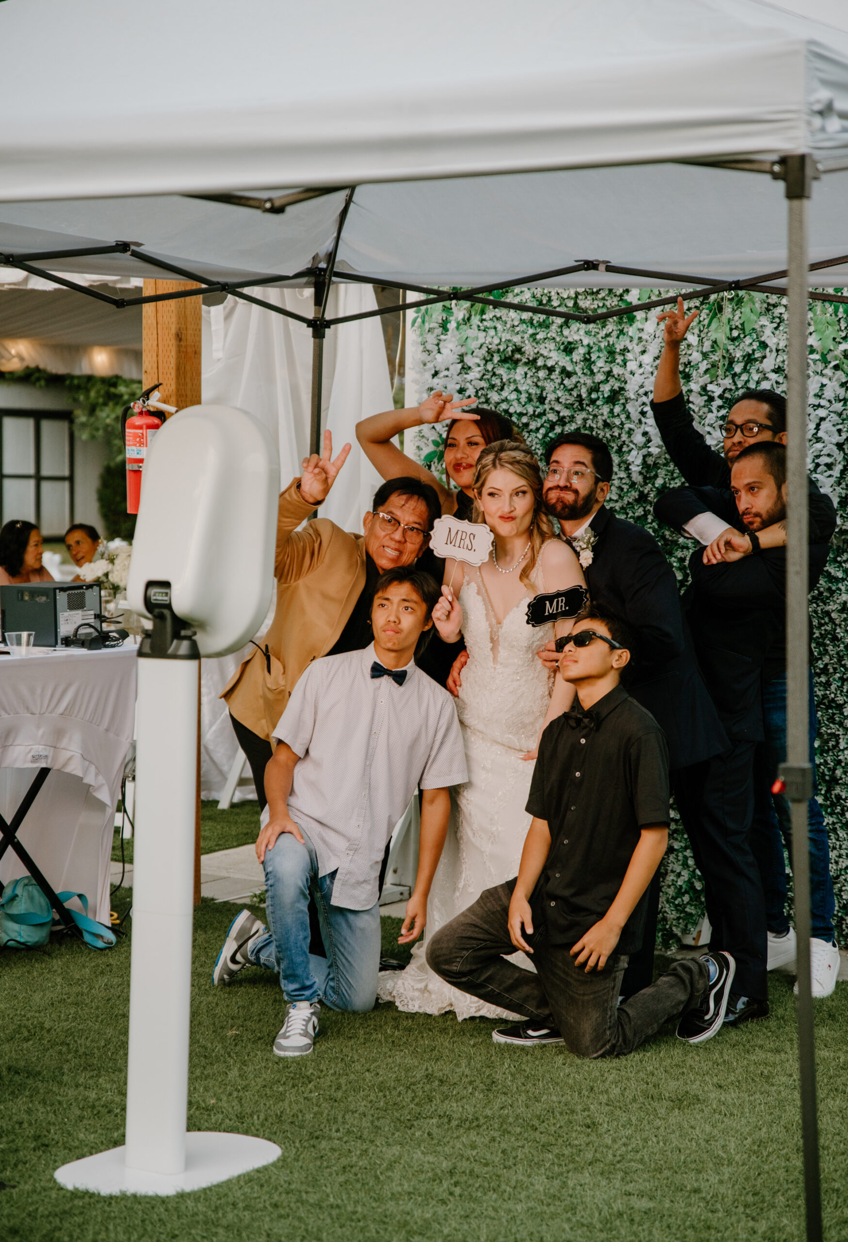 Bide and groom posing with guests in front of a photobooth