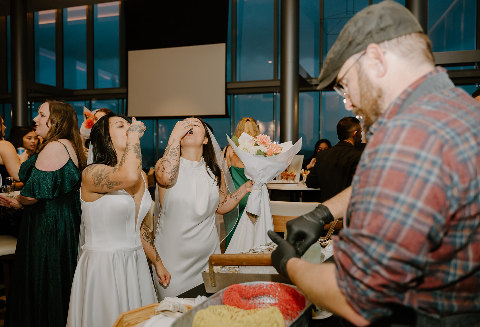 Brides eating oysters at the oyster bar at their afterparty