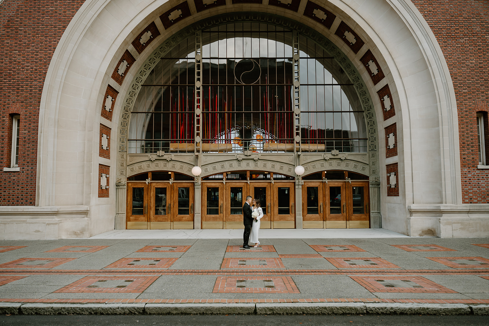 Bride and Groom taking portraits in front of the Tacoma Union after their seattle courthouse elopement