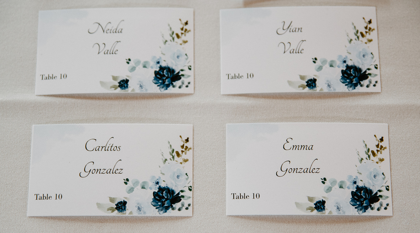 Detailed view of four wedding place cards with floral accents and assigned table numbers.