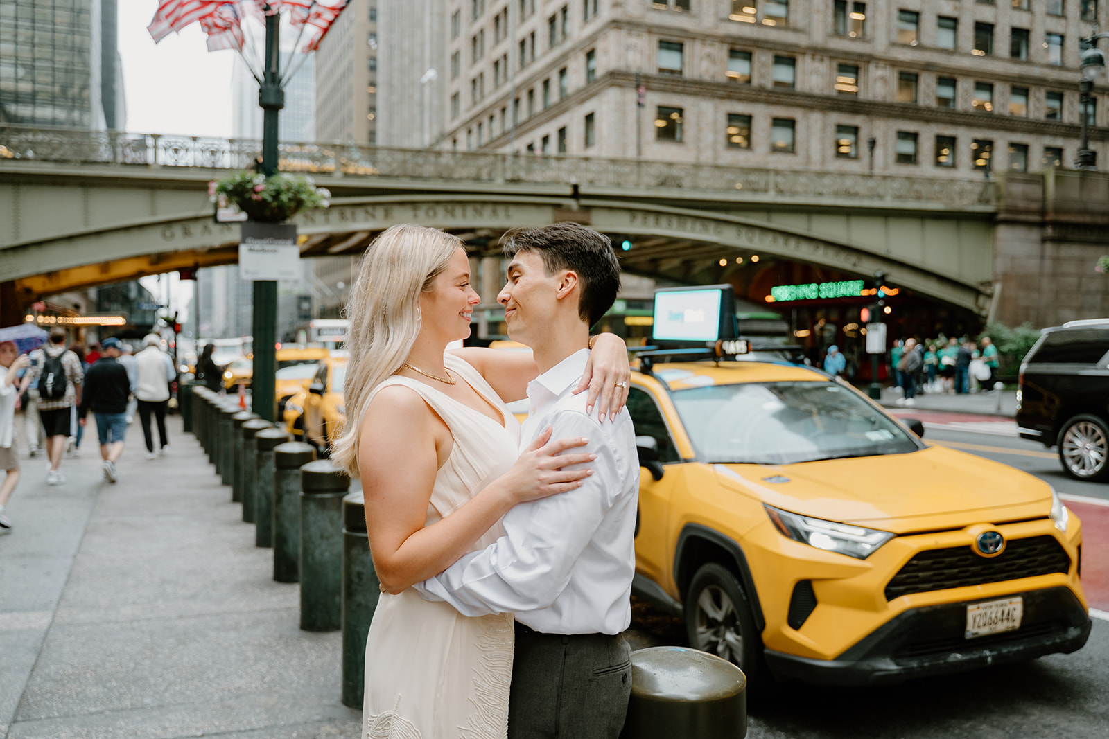 Couple hugging in the streets of NYC with taxis parked and driving behind them during their New York City Engagements
