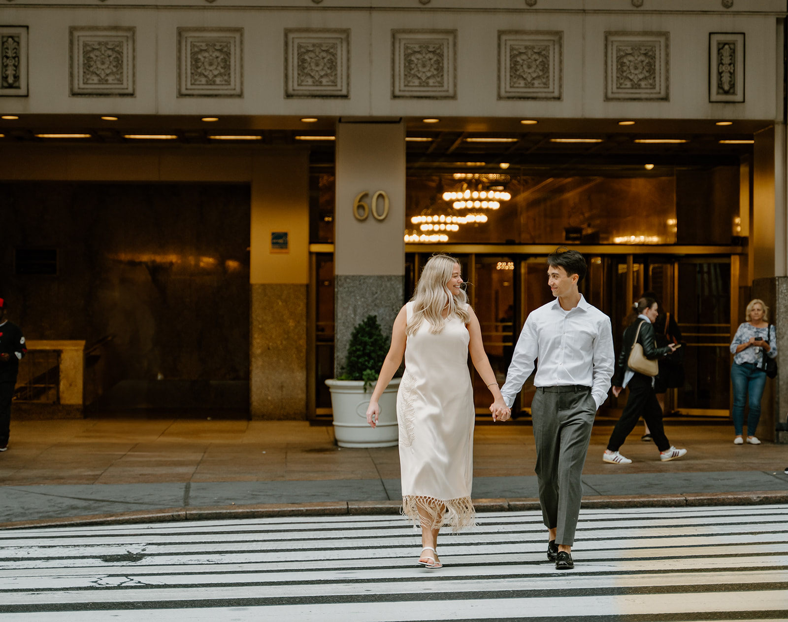 Engaged couple walking across the stress in front of the Grand Central Station during their New York City Engagements