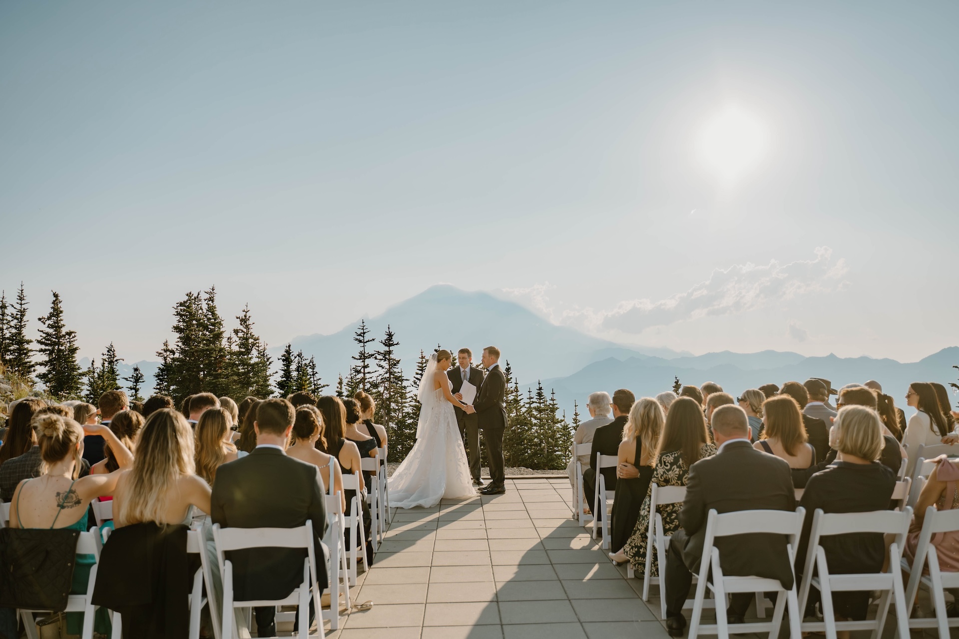 Bride and groom holding hands during their ceremony with Mount Rainier silhouetted behind them at a Crystal Mountain Resort Wedding.