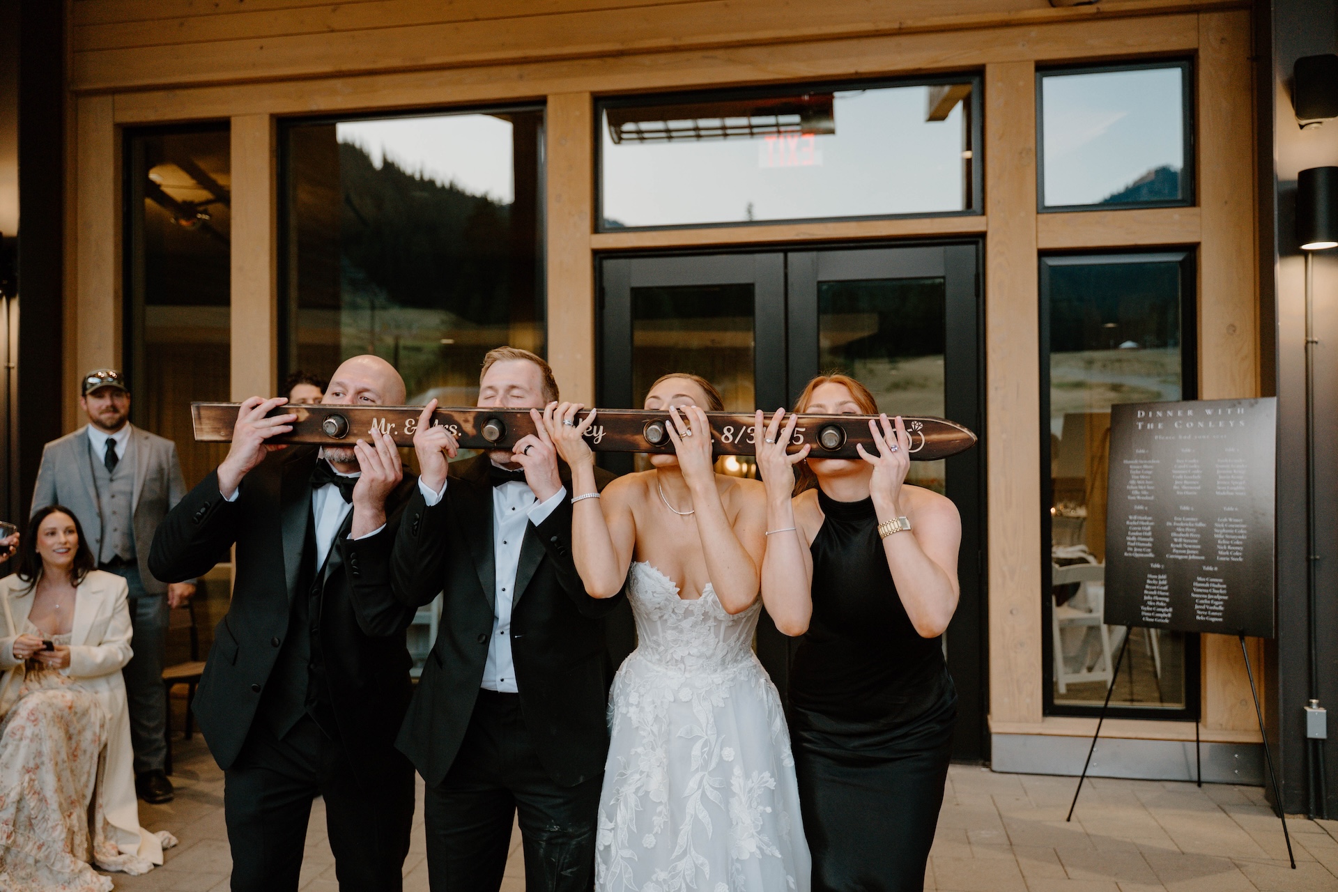 Wedding party doing a celebratory ski shot together outside the reception venue.