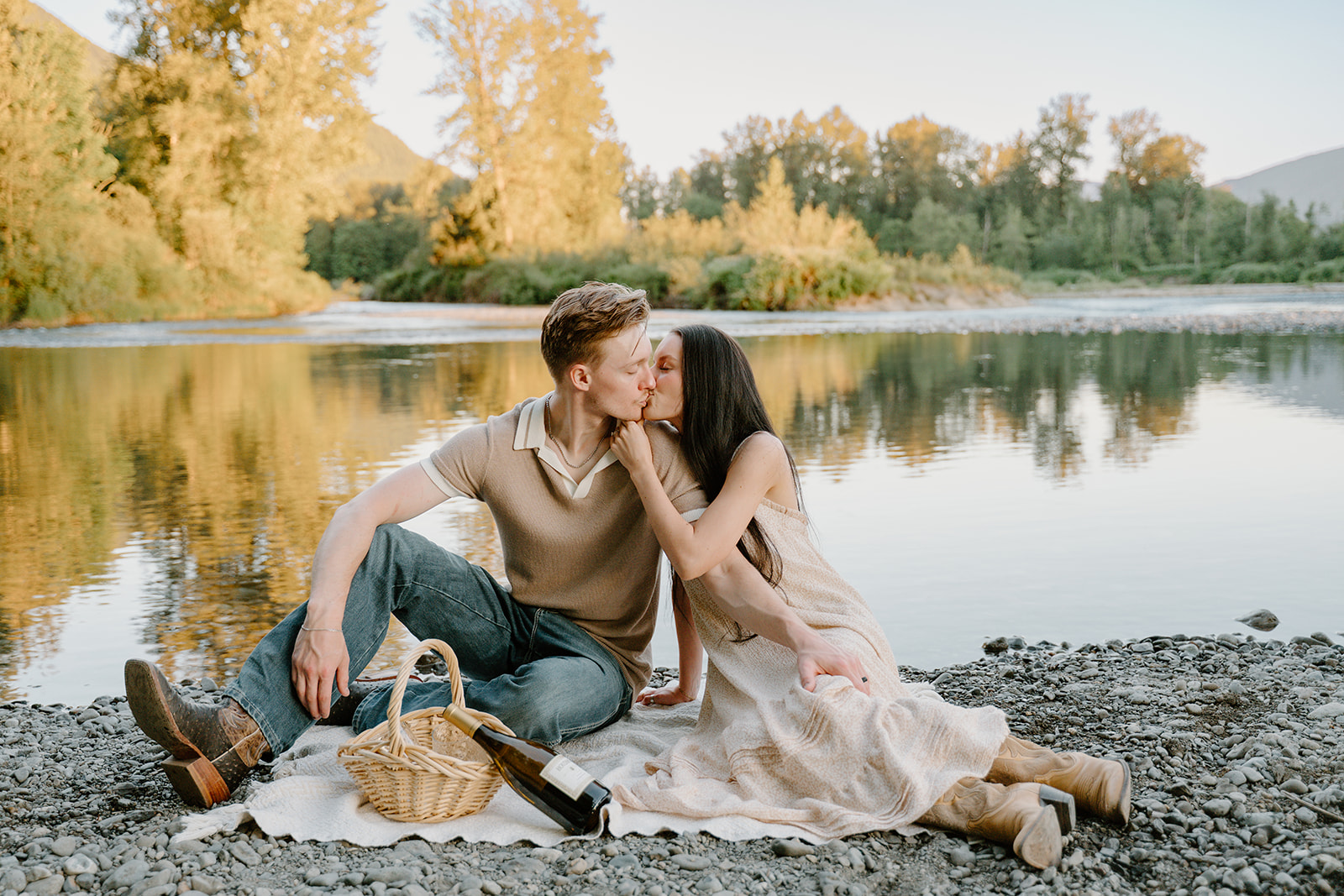 They share a quiet kiss beside the river during a picnic, framed by warm reflections ideal for Golden Hour Portraits.