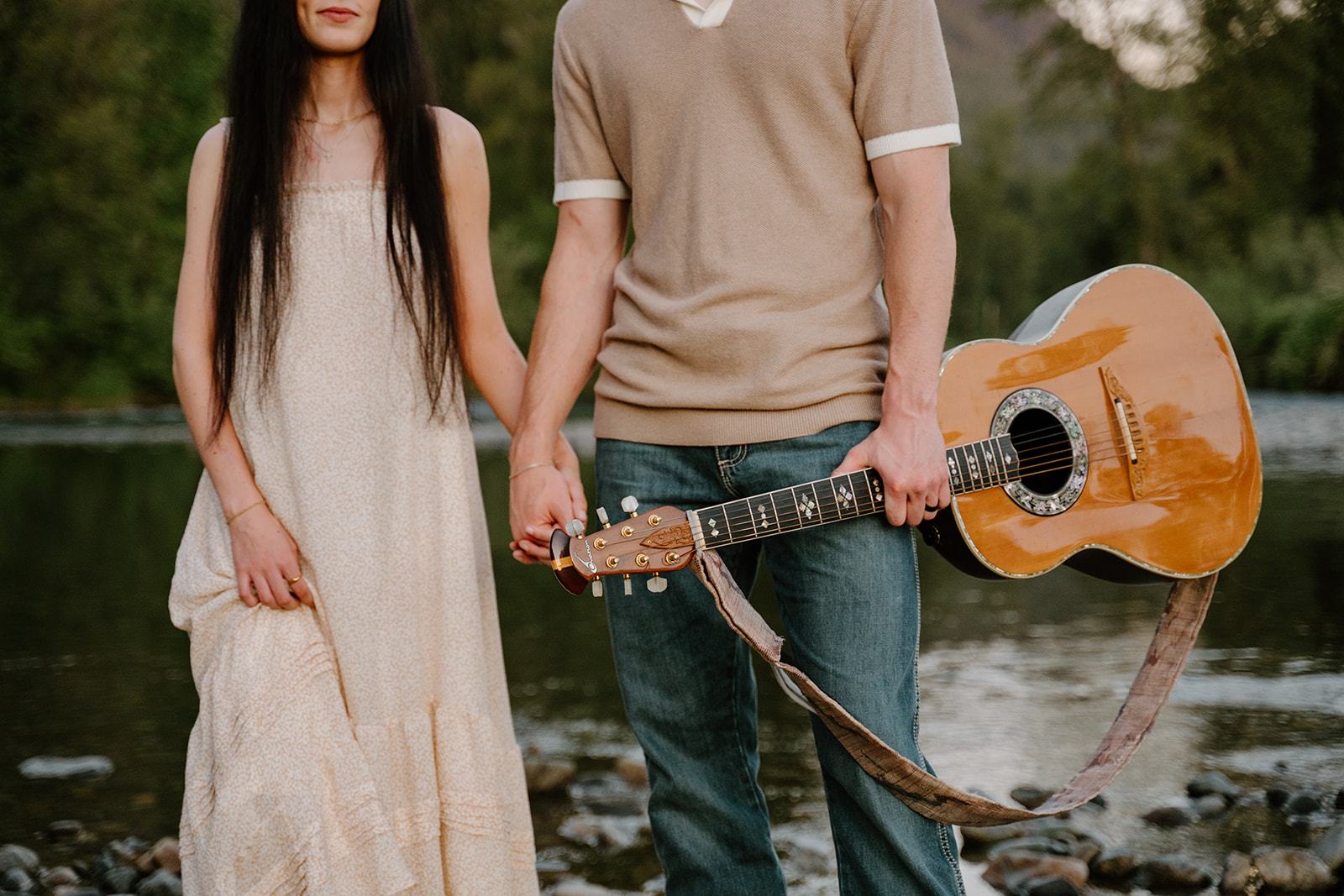 A close-up of their hands holding a guitar between them captures simple, intimate details tied to When to take engagement photos.