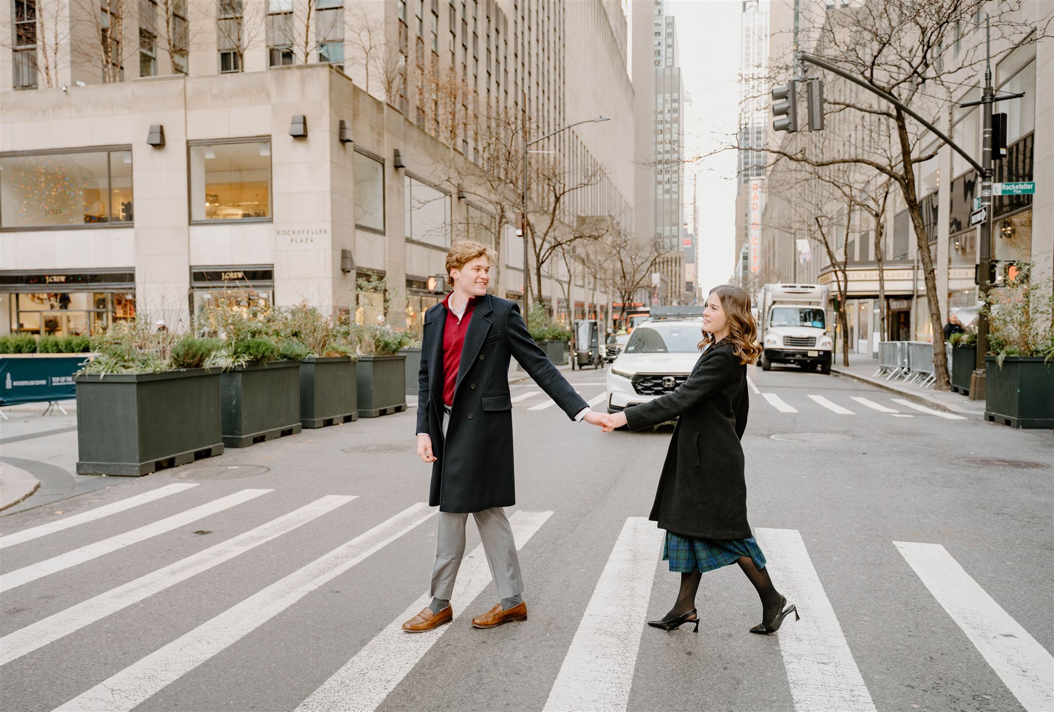 Classic engagement photos in New York of a couple crossing the street together near Rockefeller Center.
